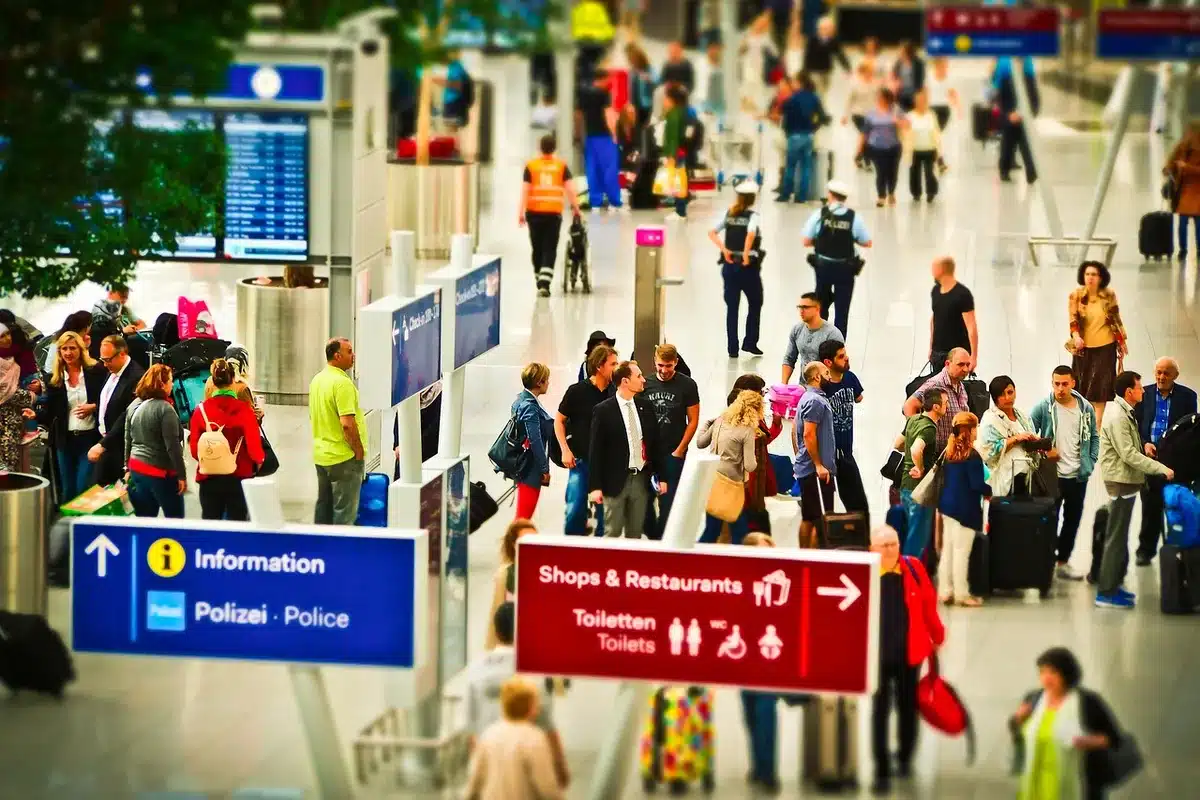 Pasażerowie i personel przy bramce na lotnisku, dokumenty i ekran odprawy