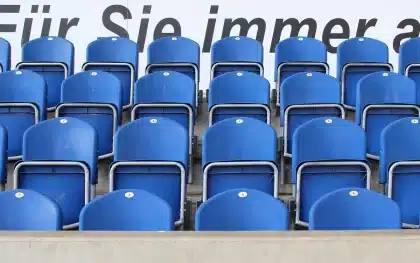 Anonimowy kibic na stadionie trzyma neutralny szalik i program meczu