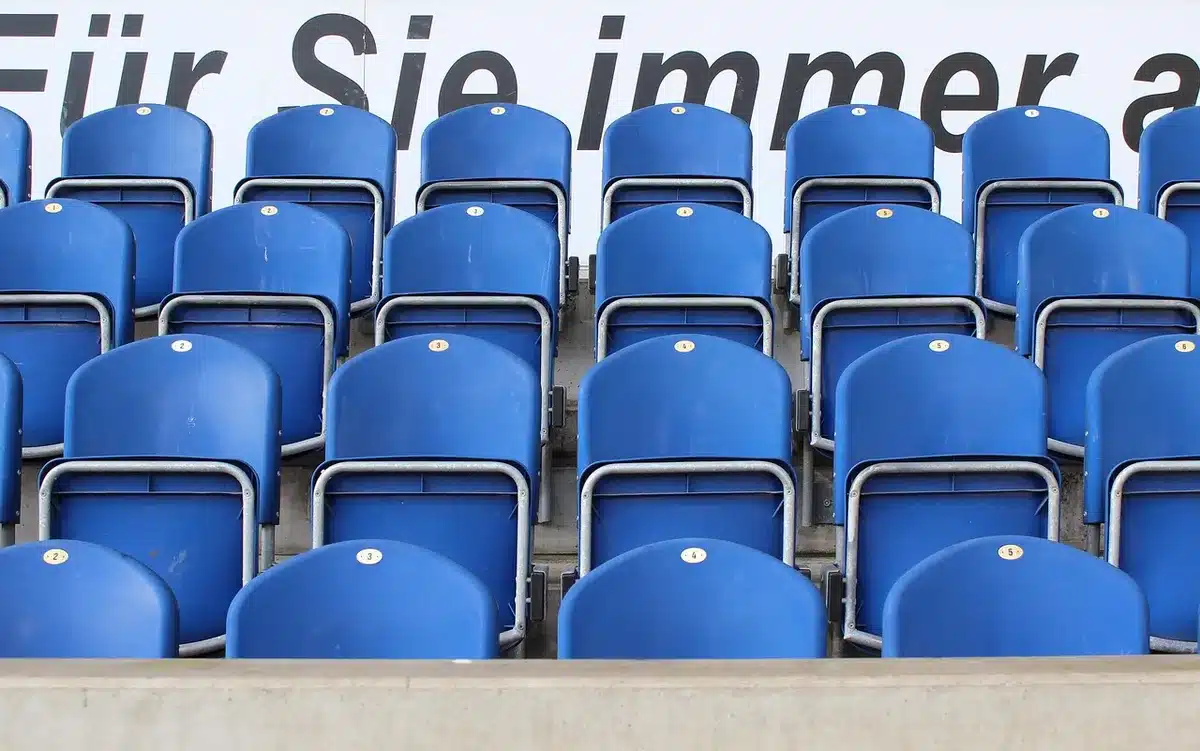 Anonimowy kibic na stadionie trzyma neutralny szalik i program meczu