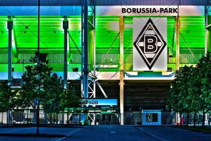 Sylwetki kibiców ze szalikami i biletami przed stadionem wieczorem