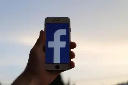 Dwie pary dłoni z telefonami pokazującymi aplikacje społecznościowe w kawiarni