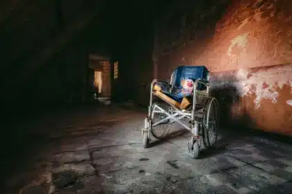 Korytarz domu opieki z pustym fotelem i wózkiem inwalidzkim